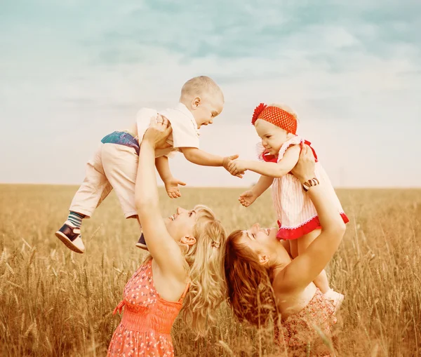 Two mothers with children in field — Stock Photo, Image