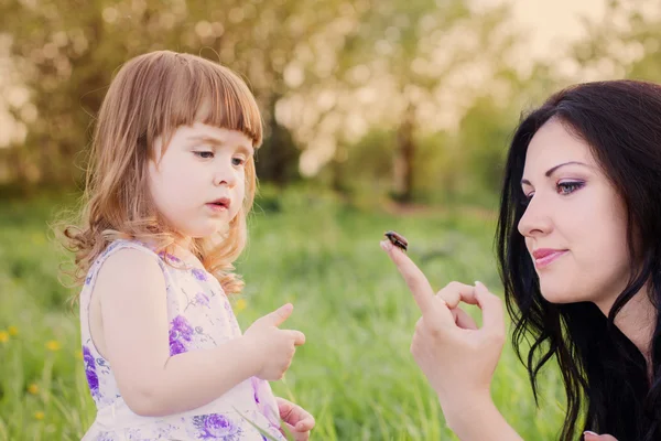 Mother and girl in garden with beetle — Stock Photo, Image