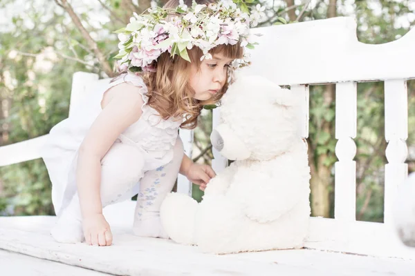 Meisje met speelgoed op witte houten bank — Stockfoto