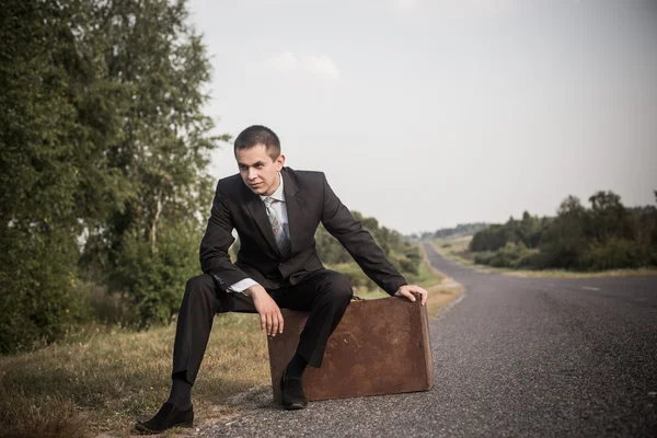 Jeune homme avec des bagages sur une route — Photo