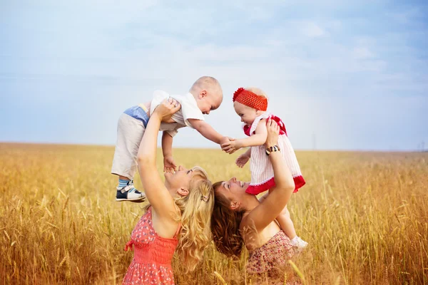 Two mothers with children in field — Stock Photo, Image