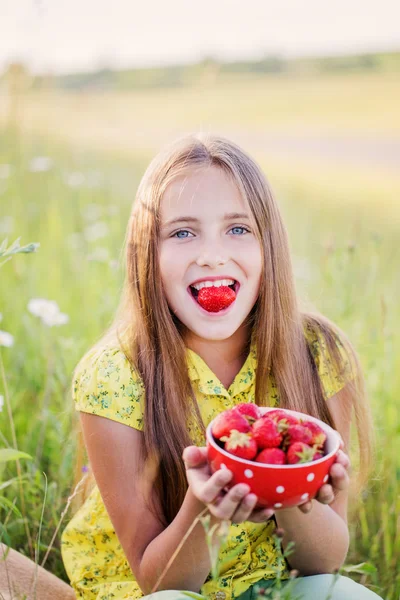 Gelukkig meisje met aardbei buiten — Stockfoto