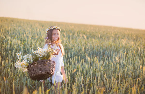 Meisje in het tarweveld met mand van bloemen — Stockfoto