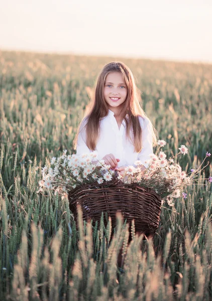 Meisje in het tarweveld met mand van bloemen — Stockfoto