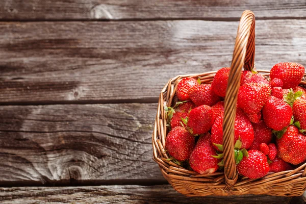 Erdbeeren im Korb auf Holzgrund — Stockfoto