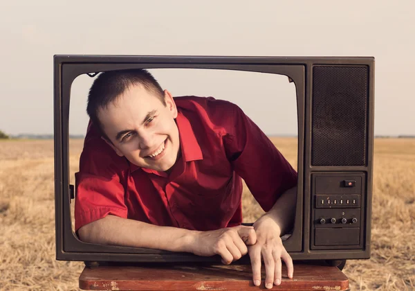 Jonge mannen met tv in de zomer veld — Stockfoto