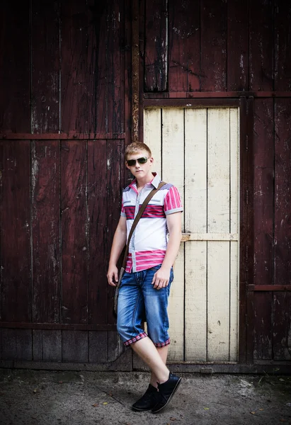 Mladý muž, který stojí vedle venkovní dřevěné stěny — Stock fotografie