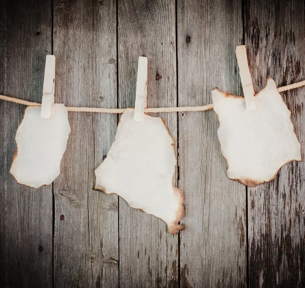 old burnt paper attach to rope with clothes pins on wooden backg