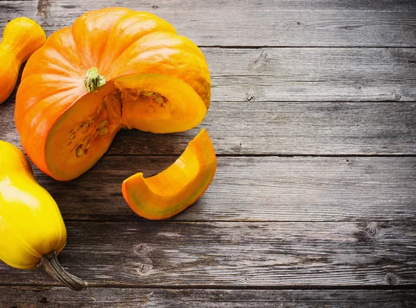 Pumpkins with leaves on wooden board — Stock Photo, Image