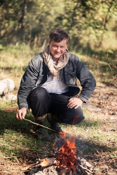 Człowiek dojrzały uśmiech siedząc przy ognisku — Zdjęcie stockowe