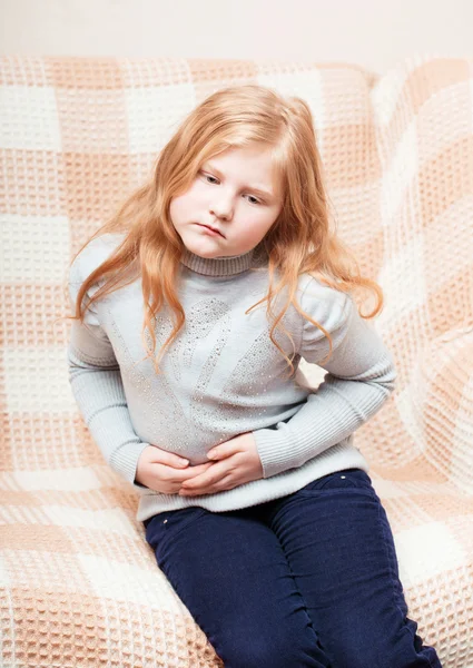 Ребенок с болью в животе в диване — стоковое фото