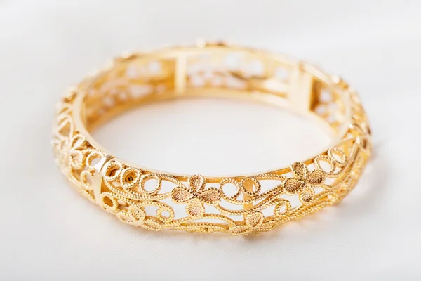 Pulsera de oro sobre tela blanca — Foto de Stock