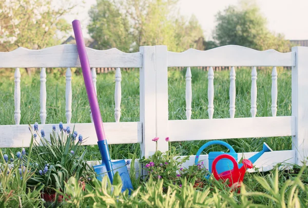 Cerca de jardim de piquete branco pintado com regador e pá — Fotografia de Stock