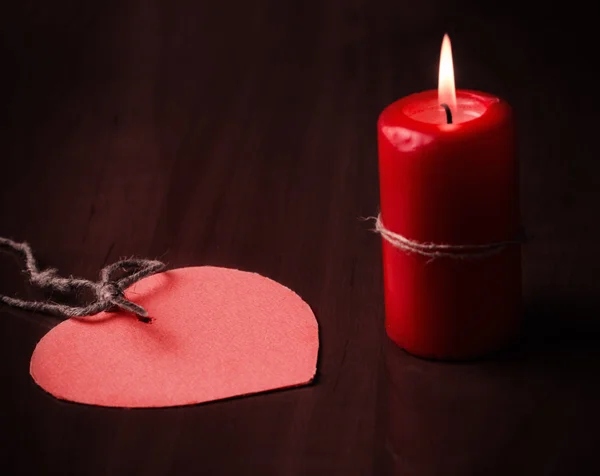 Червона свічка і паперове серце на дерев'яному столі — стокове фото