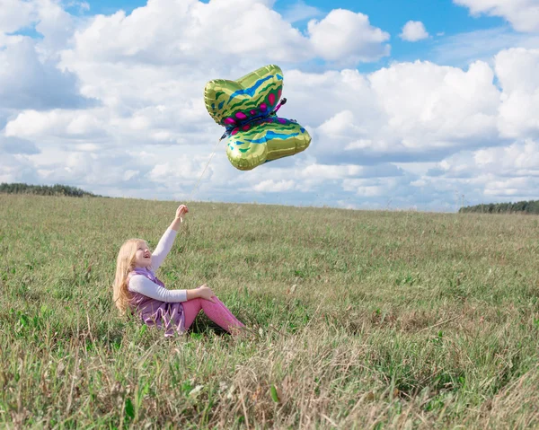 Liten flicka spelar med ballong i gräs — Stockfoto