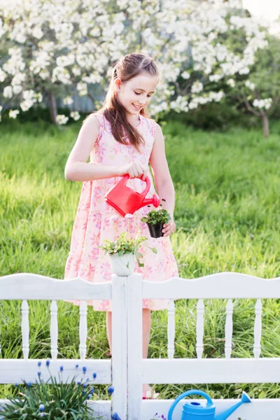 Girl watering spring flowers — Stock Photo, Image