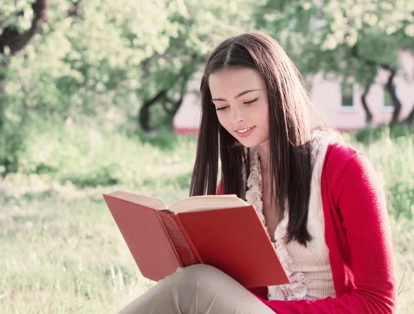 Belle fille lit livre dans un parc — Photo