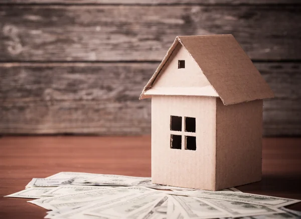 Casa dalla carta e denaro su sfondo di legno — Foto Stock