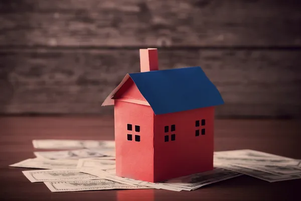 Casa do papel e dinheiro em fundo de madeira — Fotografia de Stock