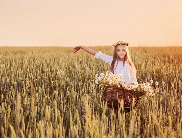 Mädchen im Weizenfeld mit Korb voller Blumen — Stockfoto