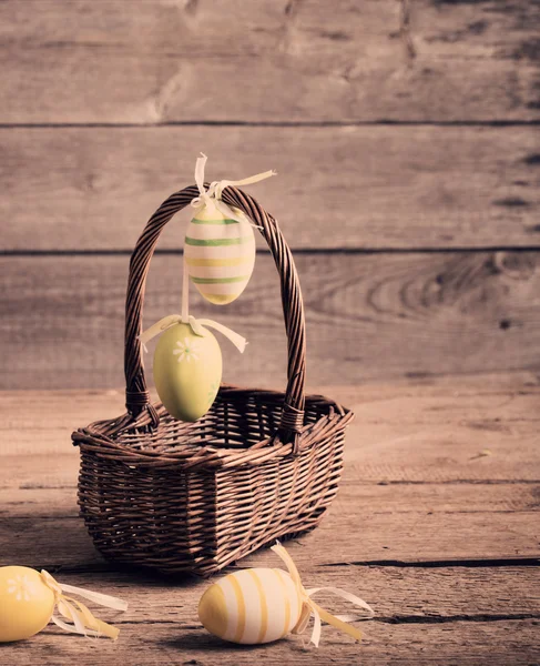 Uova di Pasqua colorate nel cestino sul tavolo di legno — Foto Stock