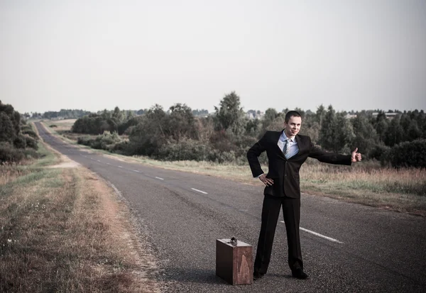 Young men hitchhiking on a road — Stock Photo, Image