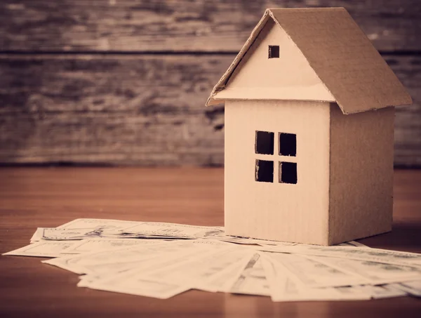 Casa do papel e dinheiro em fundo de madeira — Fotografia de Stock