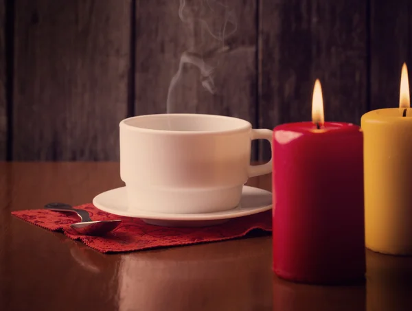 Чашка кофе и свечи на деревянном фоне — стоковое фото