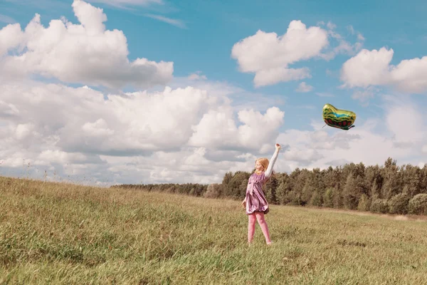 Klein meisje speelt met ballon in gras — Stockfoto