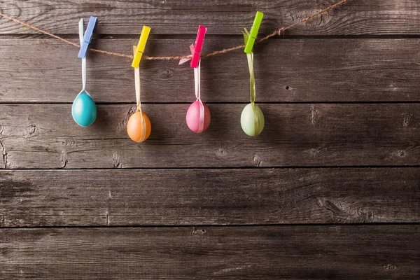 Easter eggs attach to rope with clothes pins on wooden backgroun — Stock Photo, Image