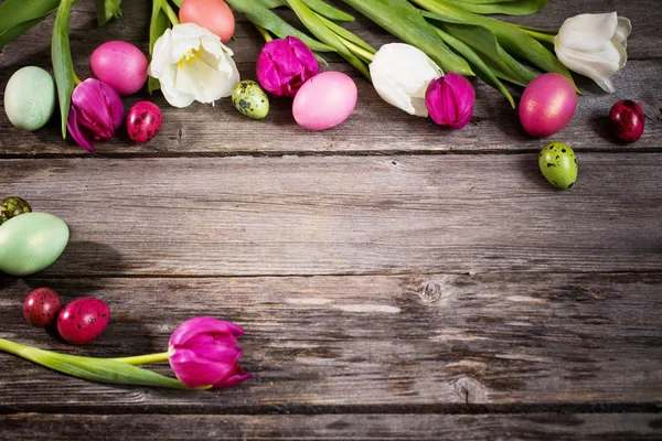Тюльпаны и пасхальные яйца на деревянном фоне — стоковое фото