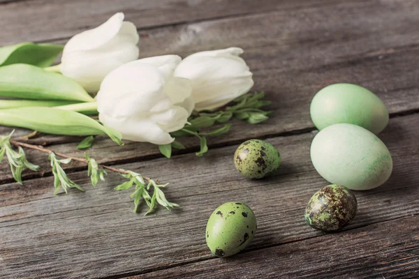 Zelená velikonoční vajíčka a tulipány na dřevěné pozadí — Stock fotografie