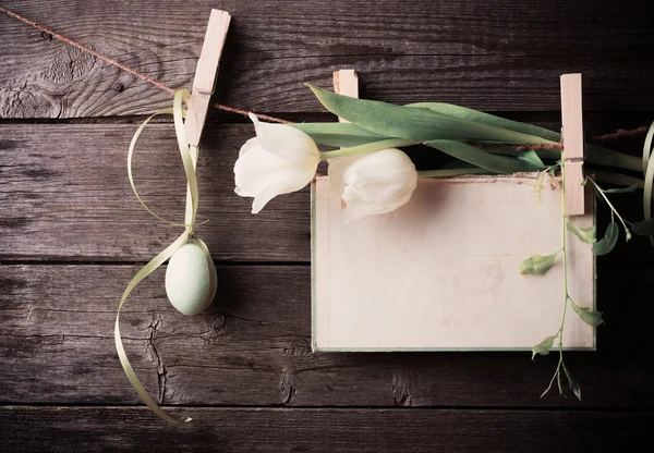 Ovo de Páscoa e papel anexar à corda com pinos de roupas e tulipas — Fotografia de Stock