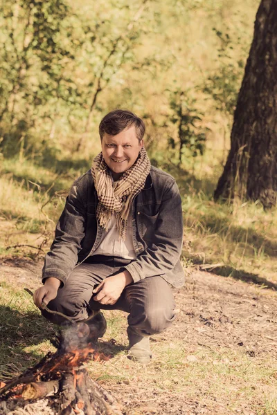 Mature smile man sitting at campfire — Stock Photo, Image