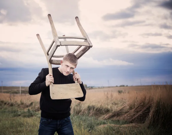 Jonge mannen met oude stoel buiten — Stockfoto