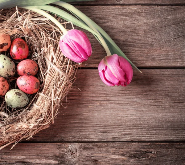 Nido di uova di Pasqua con fiori su sfondo rustico in legno — Foto Stock