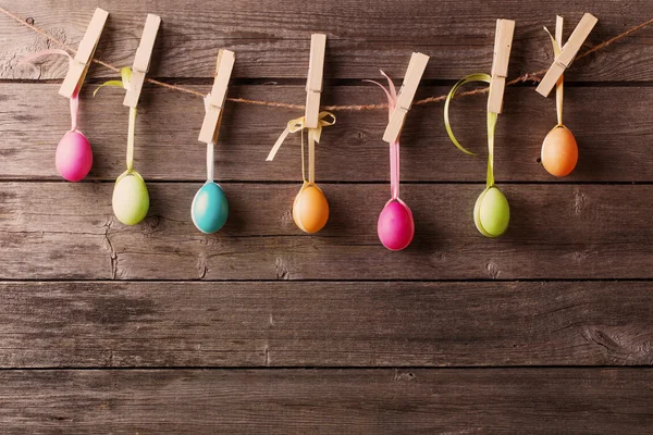 Huevos de Pascua se unen a la cuerda con alfileres de ropa en el fondo de madera —  Fotos de Stock