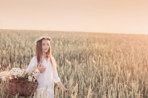 Flicka i fältet vete med korg med blommor — Stockfoto