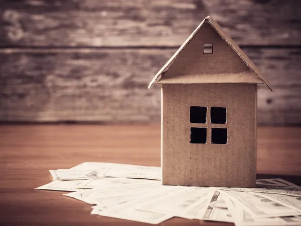 Maison du papier et de l'argent sur fond en bois — Photo