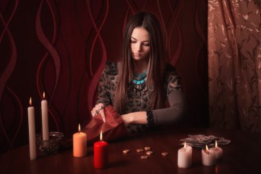 Young woman with runes and divination cards in room clipart