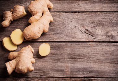 Ginger root sliced on wooden background clipart