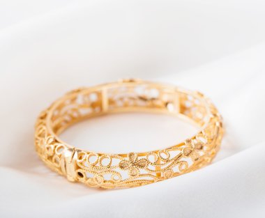 Beyaz kumaş üzerine altın bilezik