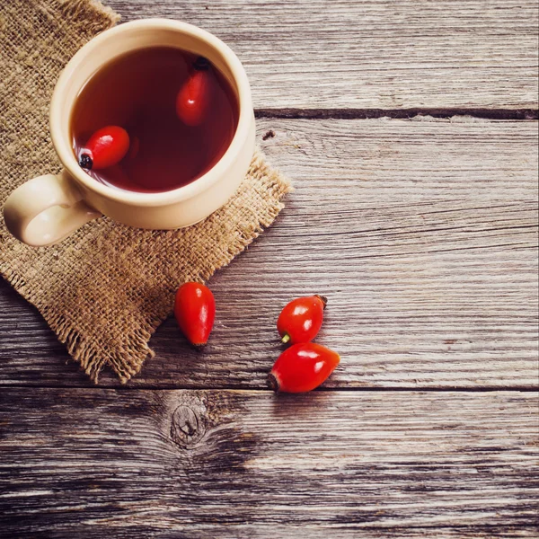 Kopje thee met hip rozen, op houten tafel — Stockfoto