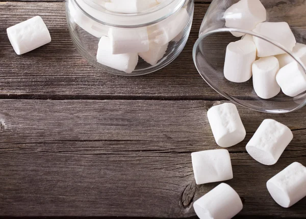 Witte marshmallows morsen uit een pot op houten achtergrond — Stockfoto