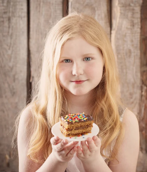 Glimlach meisje met taart op houten achtergrond — Stockfoto