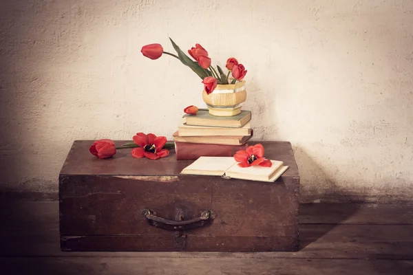 Suitcase with old books and red tulips