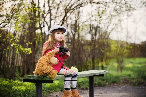 Menina engraçada no banco no parque da mola — Fotografia de Stock