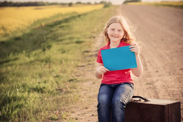 Girl with suitcase on road and holding paper — Stock Photo, Image