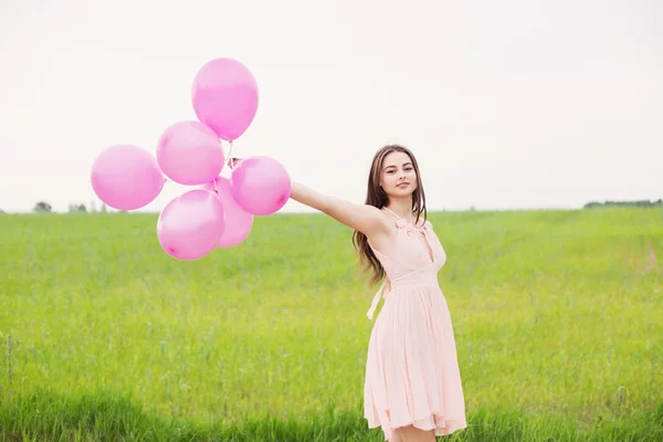 Girl with balloons  in a field — Stock Photo, Image