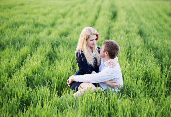 Jeune couple assis sur l'herbe verte — Photo